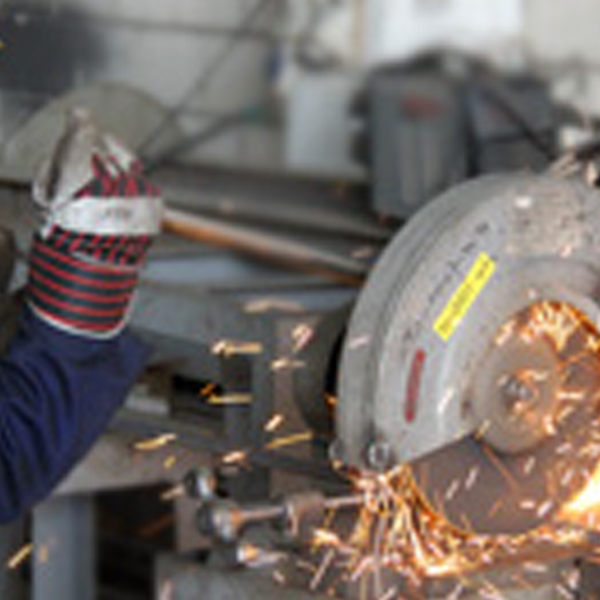 A worker grinding a pipe flange, sparks flying