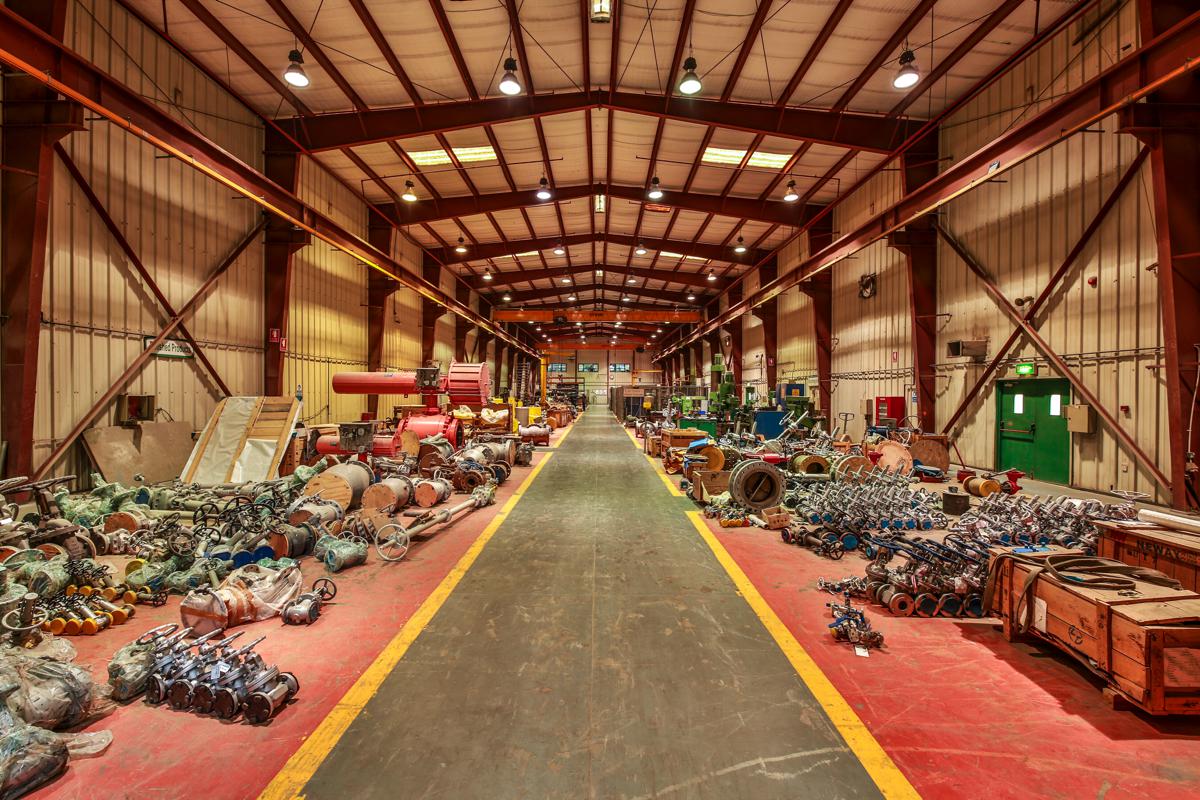 The main workshop bay, with valves and actuators laid out along both sides of the marked walkway